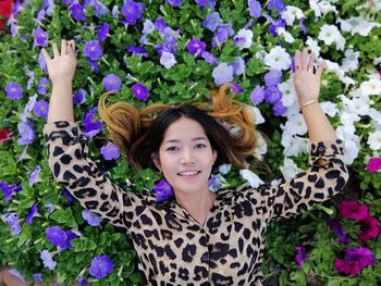 High angle portrait of smiling woman lying on flowers