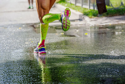 Legs female runner in compression socks running on wet asphalt