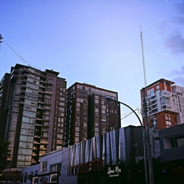 architecture, building exterior, built structure, low angle view, city, building, clear sky, sky, residential building, window, blue, residential structure, power line, outdoors, city life, office building, day, no people, street light, modern