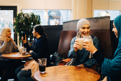 Happy female friends enjoying drinks at cafe