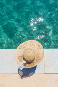 Directly above shot of woman wearing hat sitting by sea