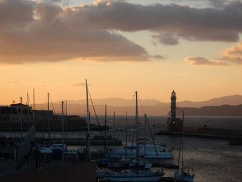 Boats moored at harbor against cloudy sky