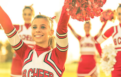 Cheerful cheerleader cheering with friends on field