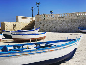 Boats moored in canal by buildings against clear blue sky