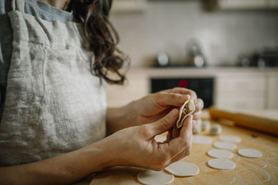 Woman preparing dumplings in kitchen at home