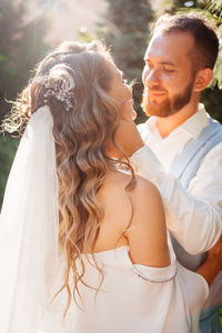 Newlywed couple embracing while standing outdoors