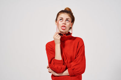 Portrait of young woman standing against white background