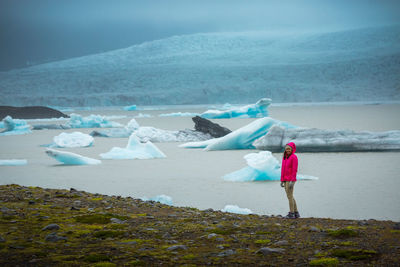 Full length of woman standing on landscape by sea against sky