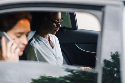 Young woman using mobile phone while sitting in car