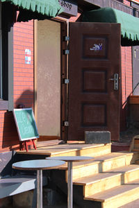 Empty chairs and table against building