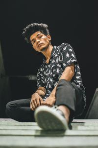 Young man looking away while sitting outdoors