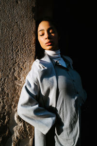 Portrait of teenage girl standing against wall