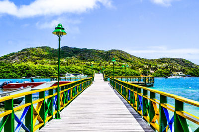 Scenic view of jetty next to hill against cloudy sky