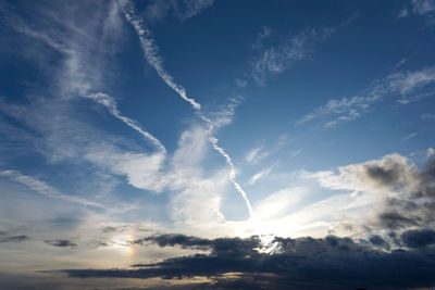 Low angle view of sunlight streaming through clouds