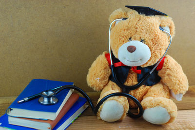 Close-up of teddy bear with stethoscope by books on table