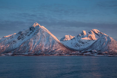 Scenic view of snowcapped mountains by sea against sky