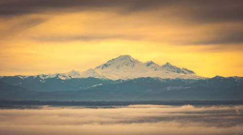 Scenic view of snowcapped mountains against cloudy sky during winter