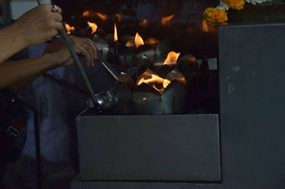 Cropped image of hand holding burning candles