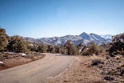 Road by mountains against clear blue sky