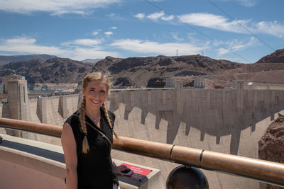 Portrait of smiling woman standing against dam