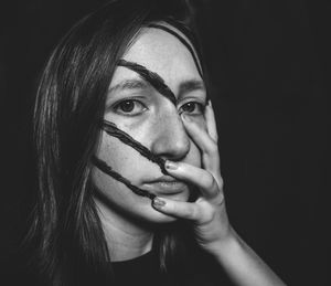 Close-up portrait of young woman against black background