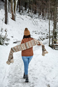 Young woman in casual clothes walking on a snowy path in the woods.