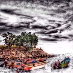 Boats in river against cloudy sky