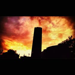 Low angle view of silhouette buildings against sunset sky