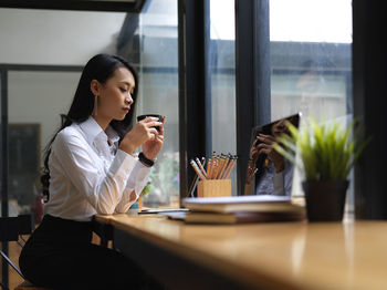 Young woman using mobile phone at table