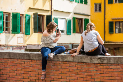 Full length of woman sitting against building