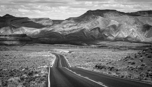 Road leading towards mountains against sky