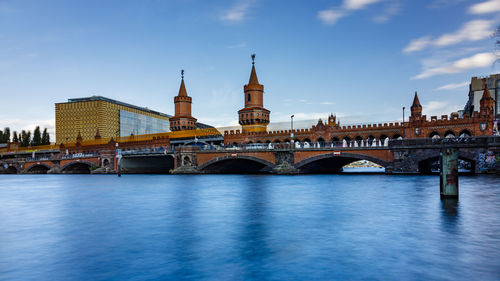 Arch bridge over river against buildings in city