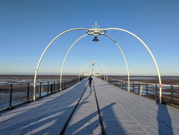 Pier over sea against clear blue sky