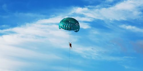 Low angle view of person paragliding against sky