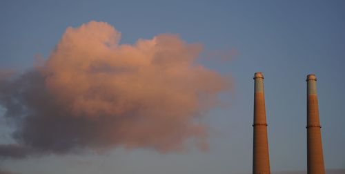 Low angle view of smoke emitting from chimney against sky