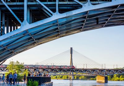 Suspension bridge in city against clear sky