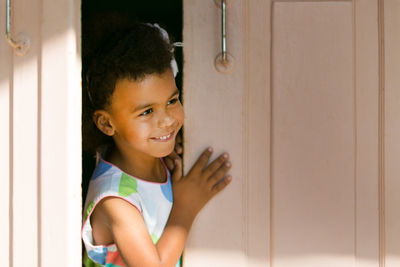 Portrait of smiling girl standing against door