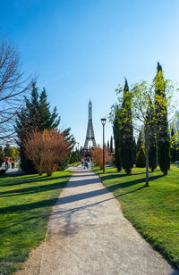 Footpath amidst trees in park against sky