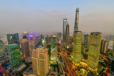 Illuminated modern buildings in city against sky