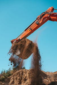 Low angle view of crane at construction site against clear blue sky