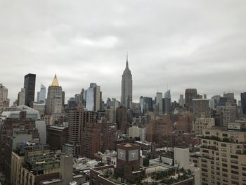 Aerial view of buildings in city against cloudy sky