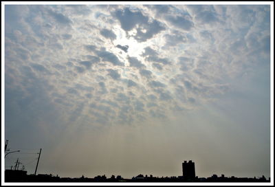 Low angle view of silhouette trees against cloudy sky