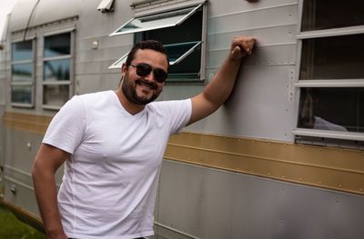 Portrait of smiling young man wearing sunglasses standing by motor home