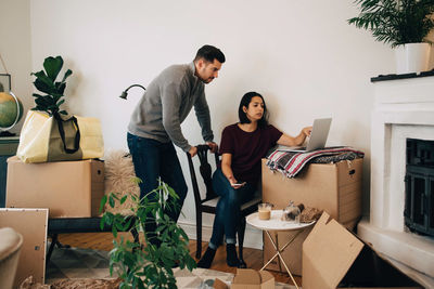 Woman showing laptop to man while moving at new home
