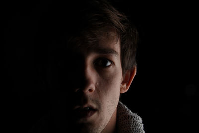 Close-up portrait of serious young man over black background