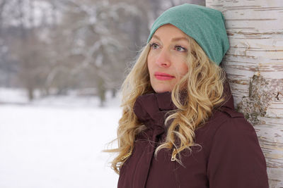 Blond woman with headband against tree in park