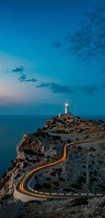 Lighthouse by sea against blue sky