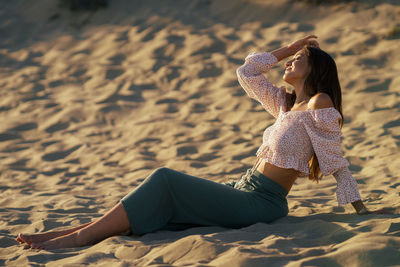 Full length of woman relaxing on sand at beach