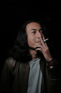 Man smoking cigarette against black background