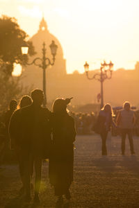 Silhouette of people in town square during sunset